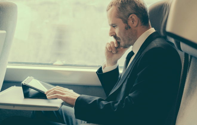 Homem que trabalha em seu laptop, enquanto em uma viagem de trem de Negócios